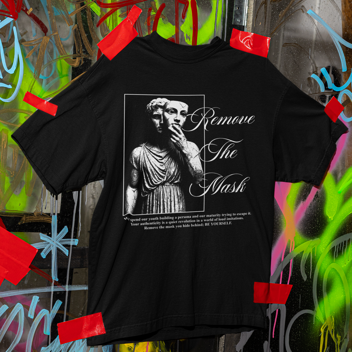 Black t-shirt with graphic design and text on a graffiti-covered wall background