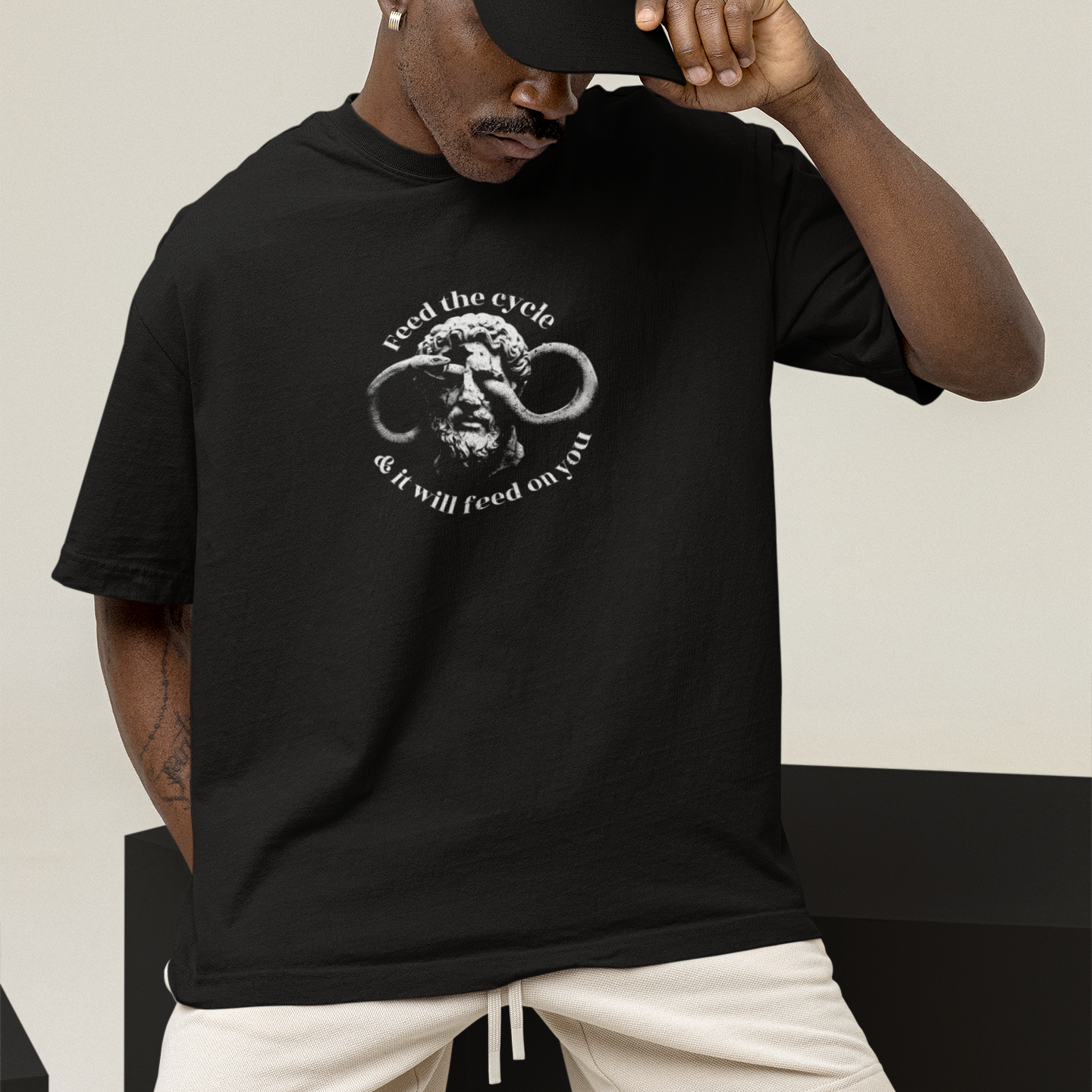 Man wearing a black t-shirt with a graphic design and text, standing against a neutral background.