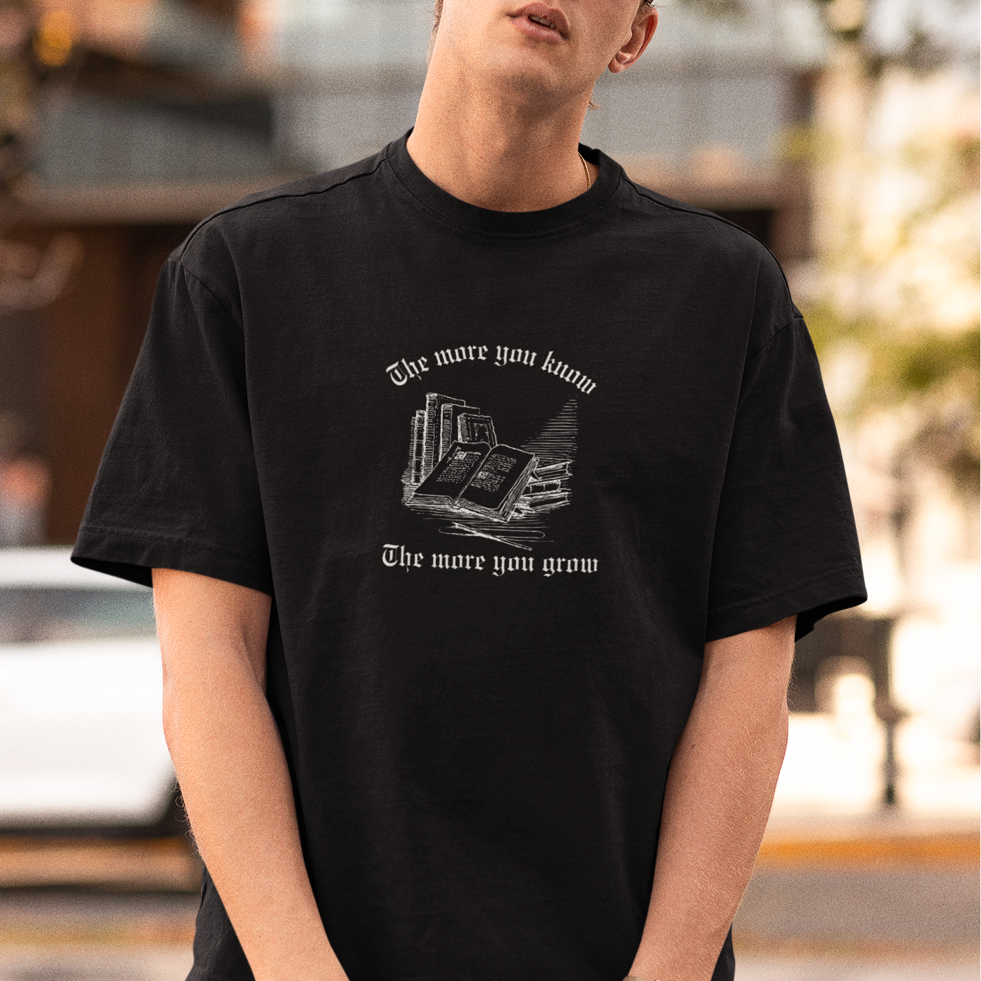 Person wearing a black t-shirt with graphic design and text, standing outdoors.